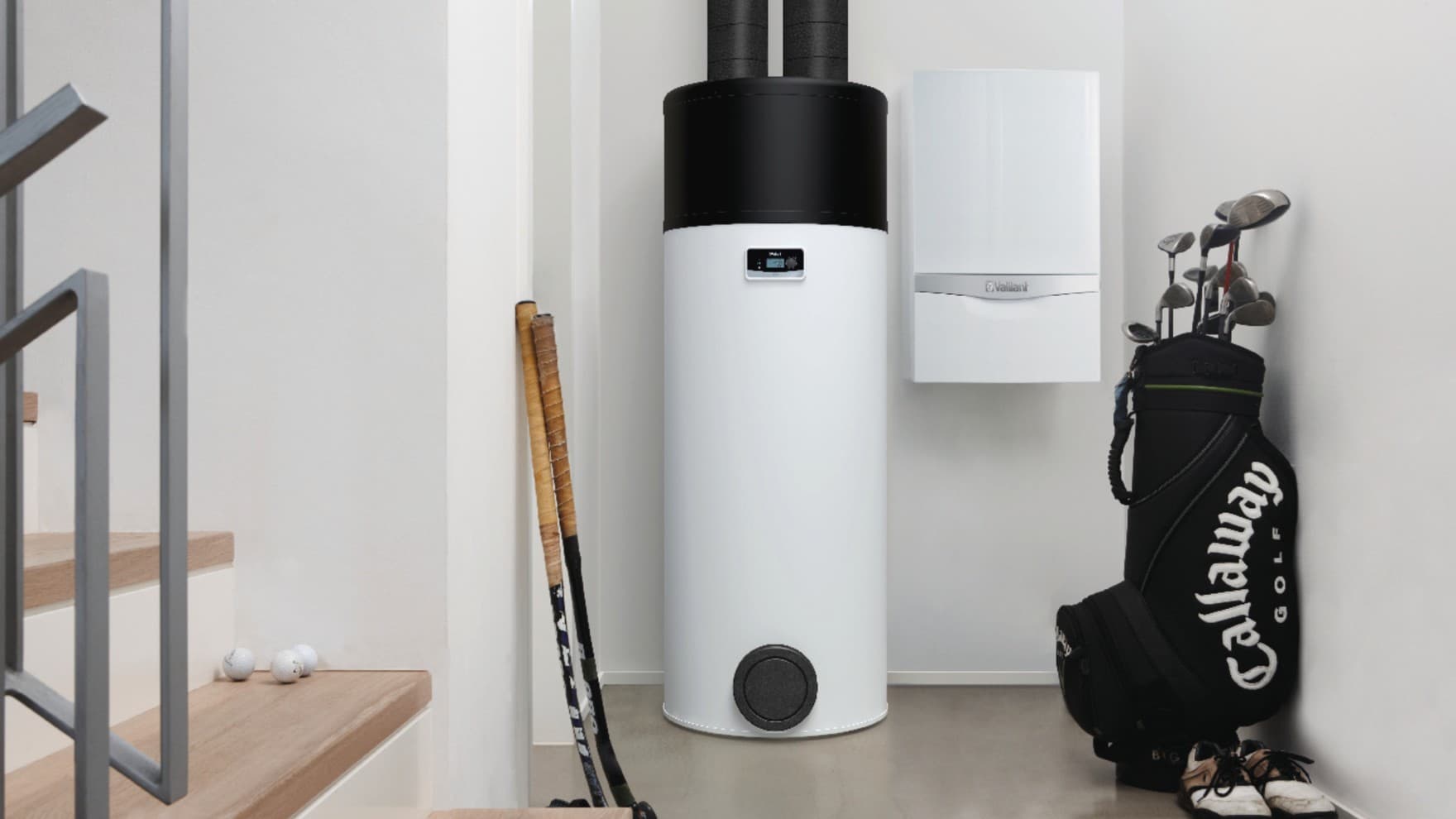 In einem Heizungskeller steht eine Warmwasser-Wärmepumpe neben einem an der Wand hängenden Gas-Brennwertgerät, links davon stehen zwei Hockey-Schläger, rechts davon eine Golftasche