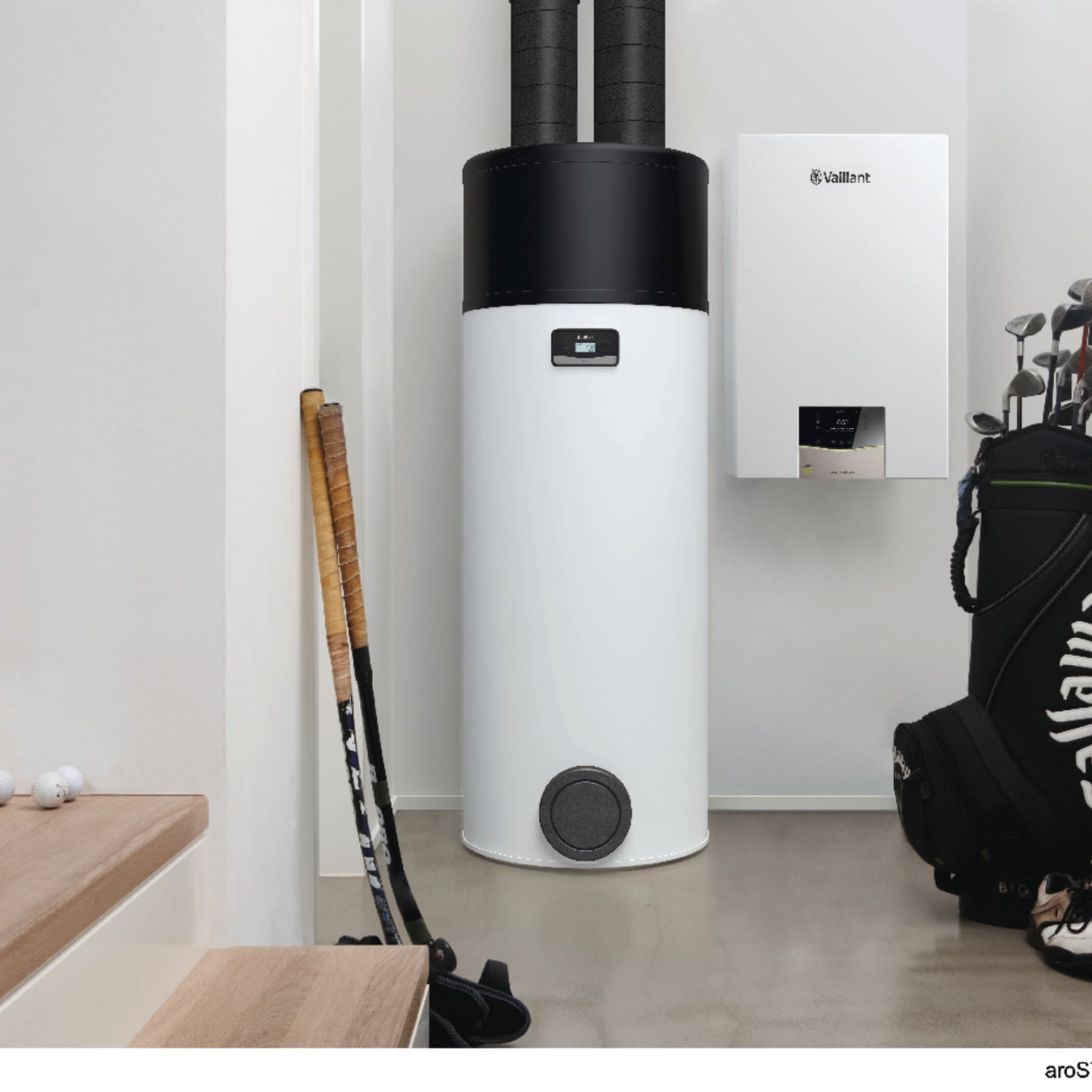 Eine Warmwasser Wärmepumpe von Vaillant steht neben einer hängenden Gasheizung von Vaillant in einem Kellerraum.