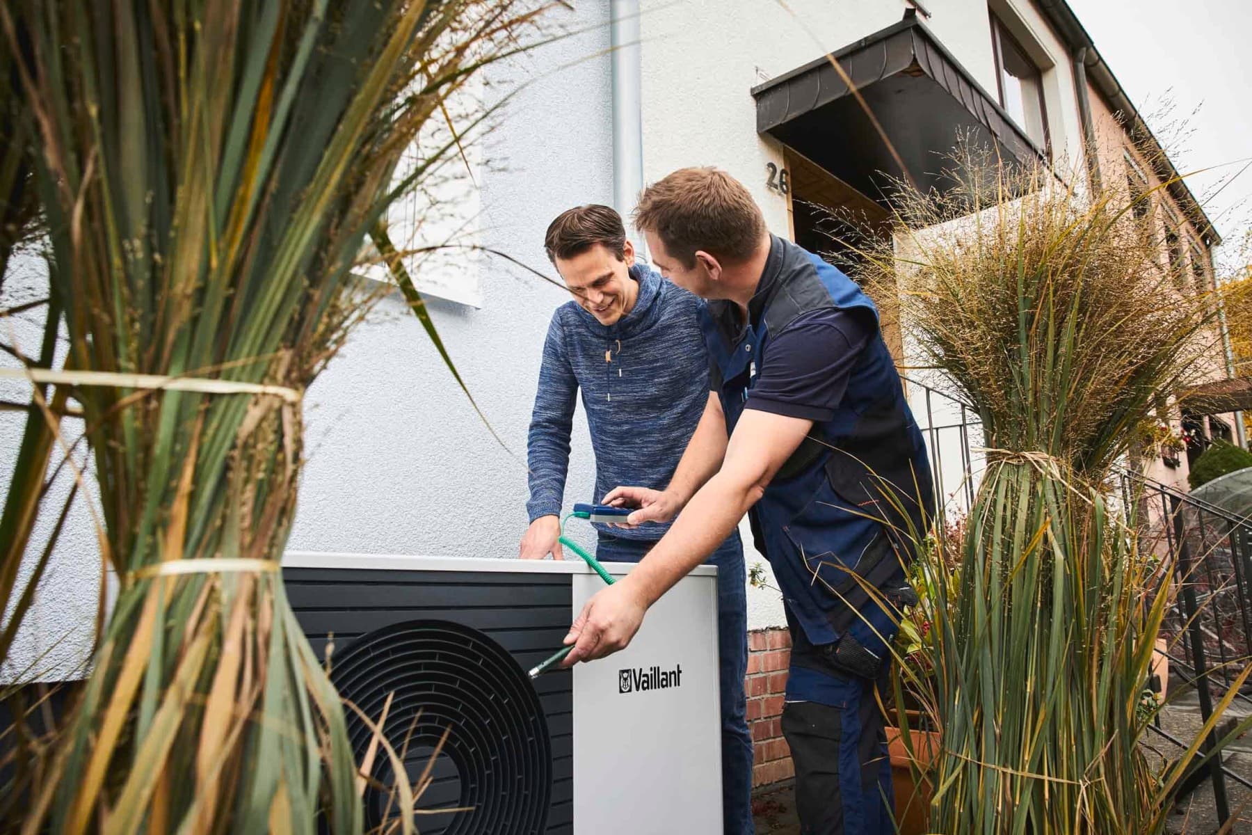 Zwei Männer stehen an der Außeneinheit einer Wärmepumpe