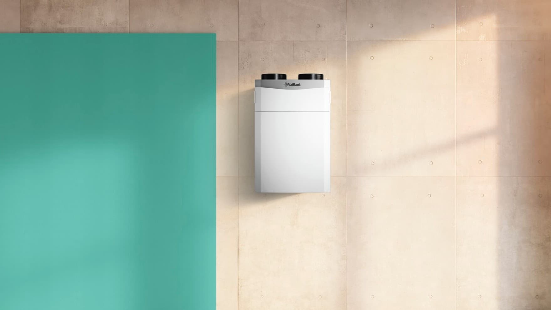 Eine Vaillant Lüftungsanlage hängt an einer Steinwand, daneben ist eine grüne Wand zu sehen.