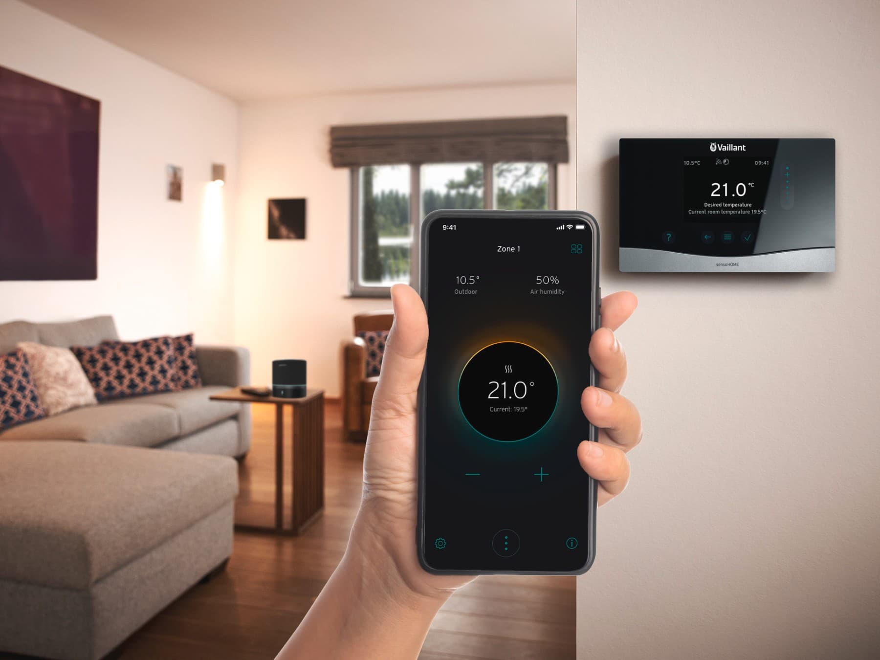 Eine Hand vor einem Vaillant Regler, die ein Smartphone hält, auf dem die myVaillant App zu sehen ist.