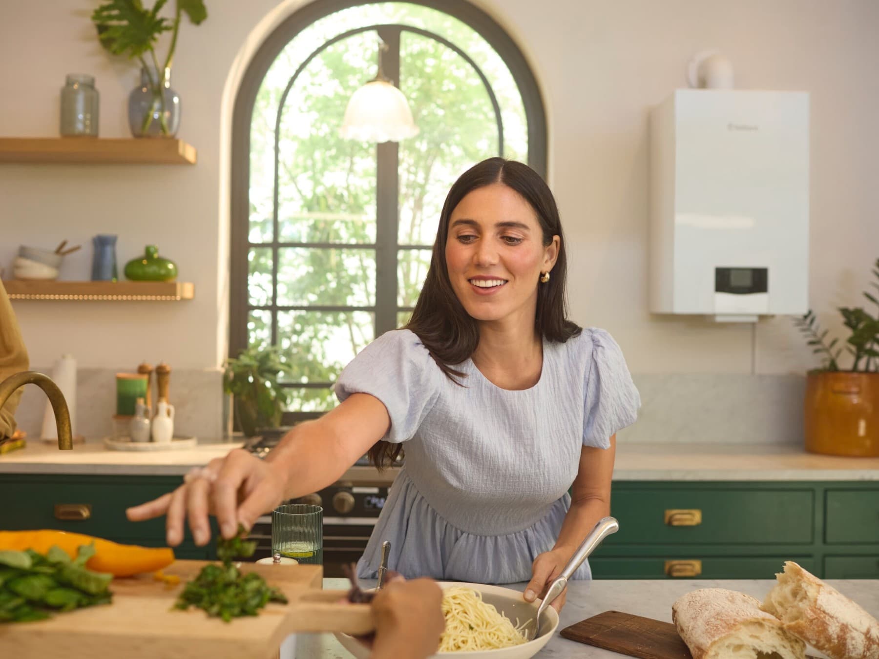 Eine Frau steht in einer Küche, in der im Hintergrund neben dem Fenster ein Vaillant Gas-Wandgerät hängt.