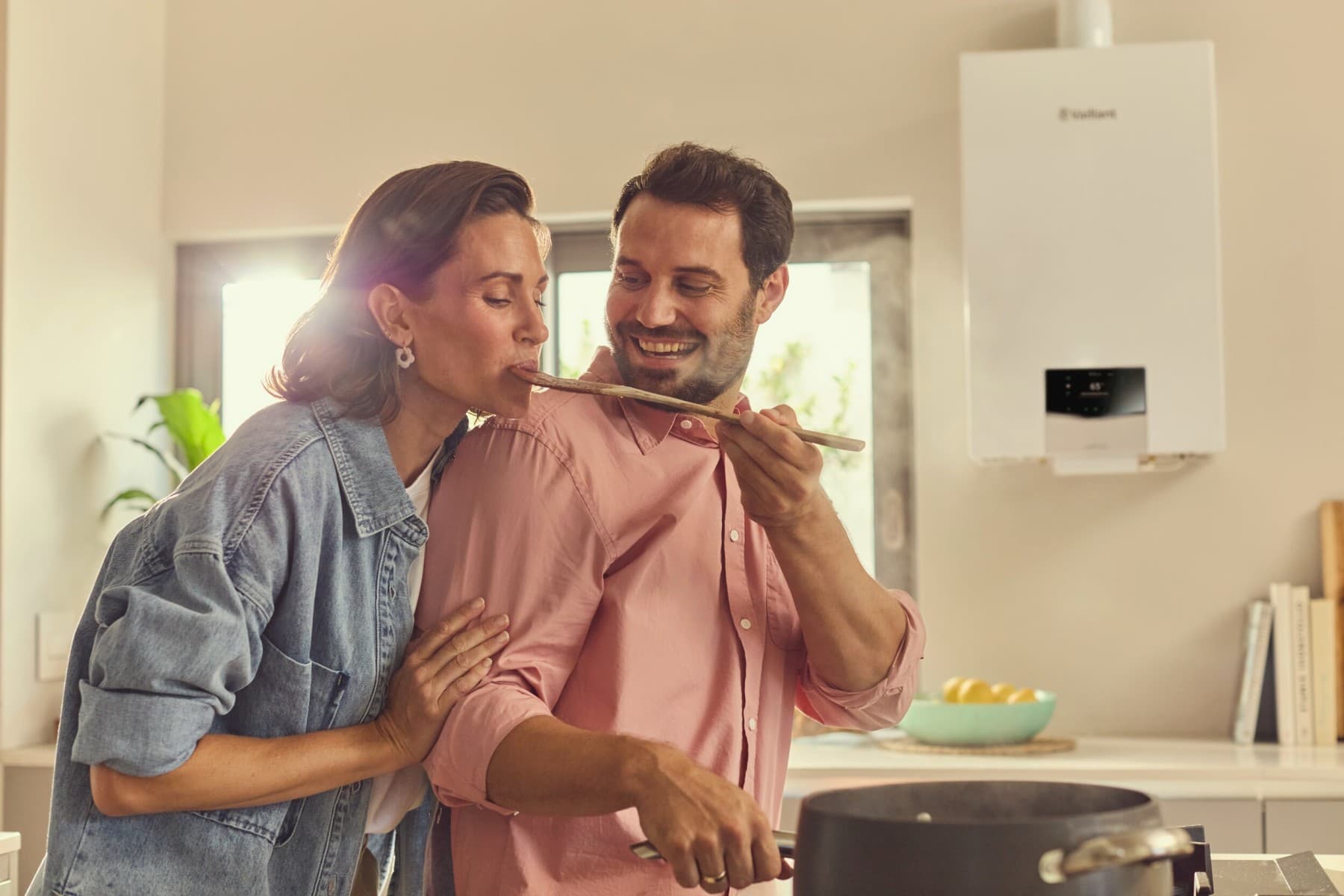Ein Mann und eine Frau stehen in der Küche am Herd, im Hintergrund hängt eine Vaillant Gasheizung.