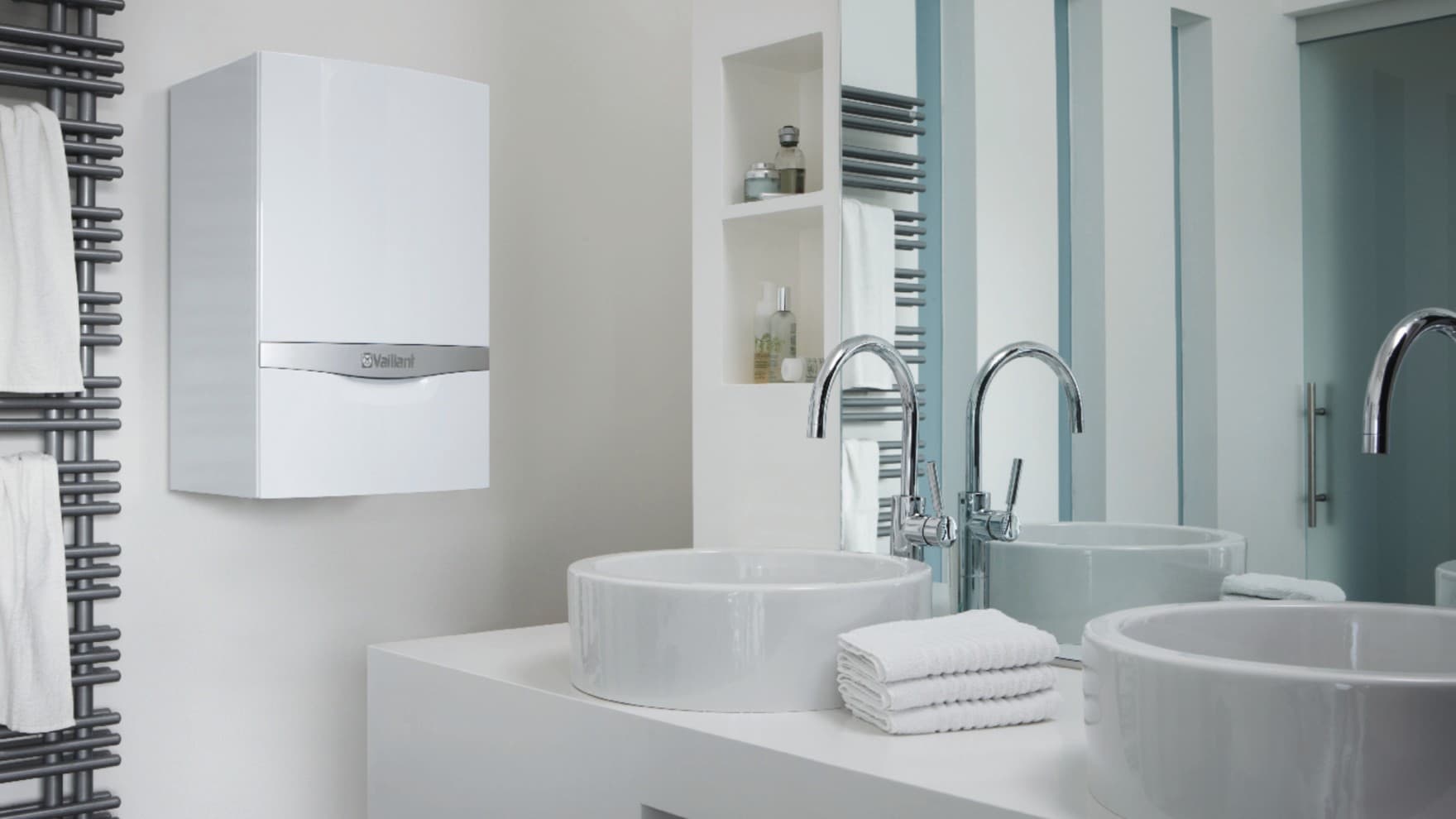 Ein ecoTEC plus Gerät von Vaillant hängt in einem Bad neben dem Waschbecken an der Wand